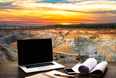 an open pit mine at sunset with a computer and paperwork