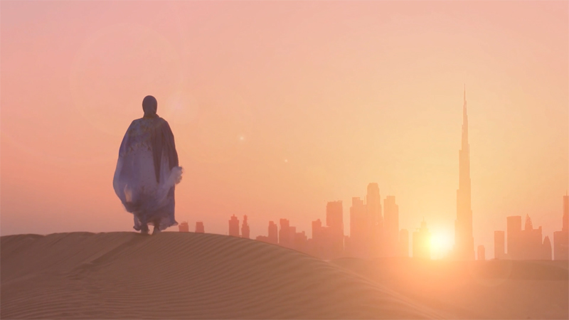 A woman in Muslim dress watching a sunrise over Dubai