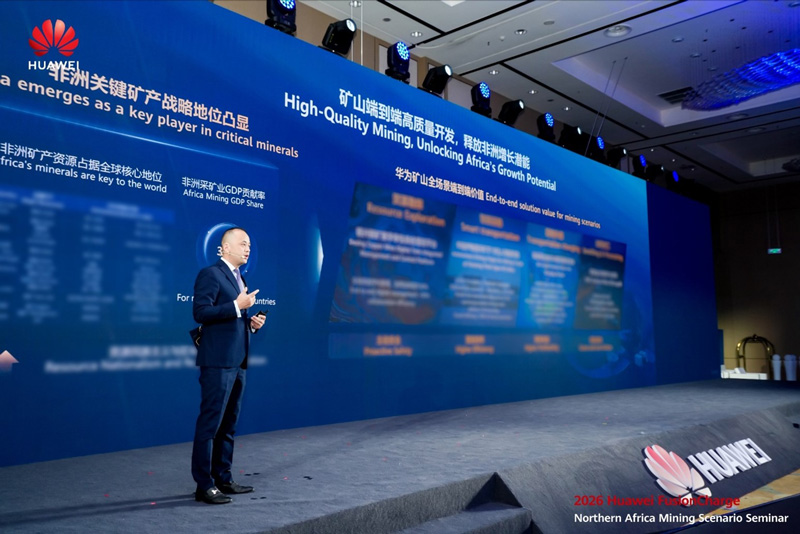 Huawei's Philippe Wang standing on a stage speaking in front of a large backdrop filled with text
